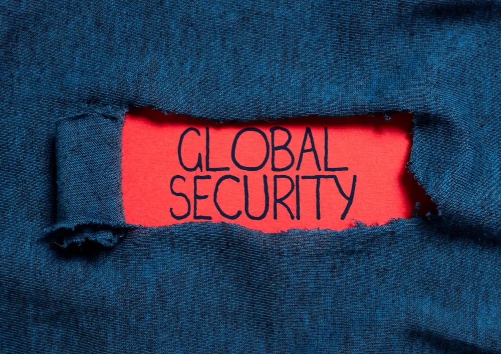 Blue fabric with a ripped hole with the text global security on a red paper.