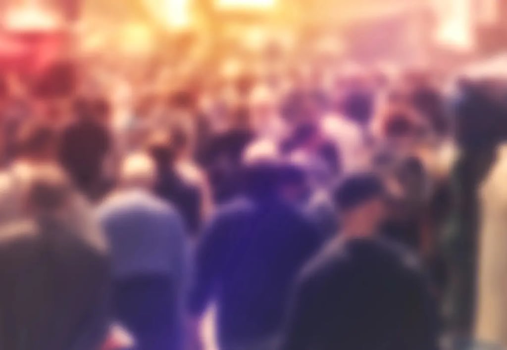 An very diffuse image with a crowd of people walking on a city street.