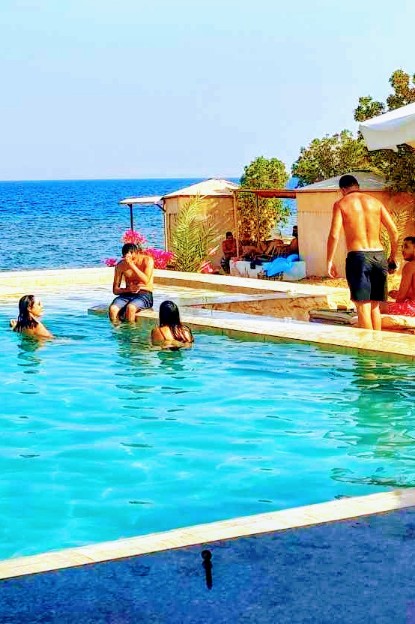 People in pool in front of the sea