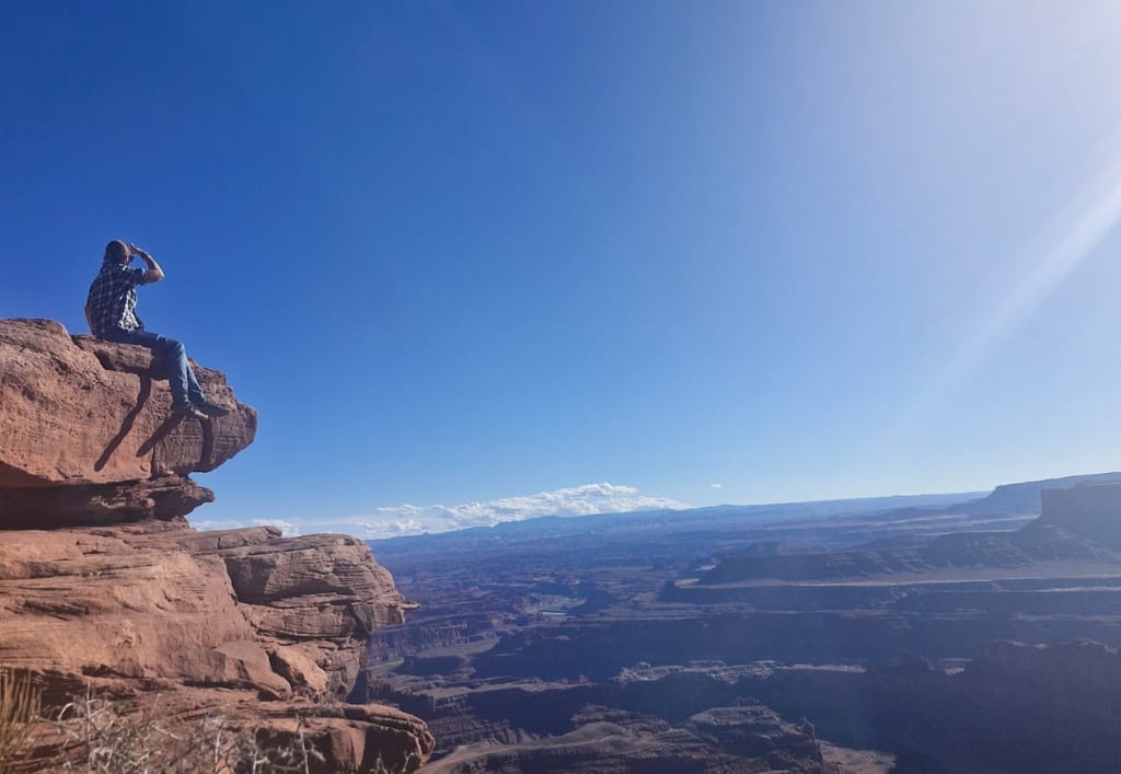 a woman sitting on a rock formation on a sunny day