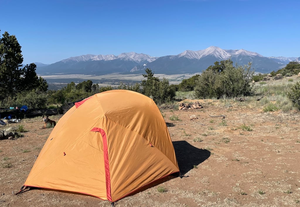 a tent pitched up in a field with mountains in the background