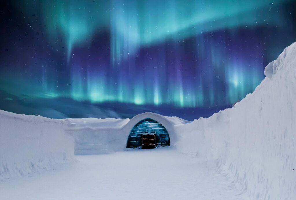 Igloo-style snow shelter under northern lights, arctic survival and cold weather camp