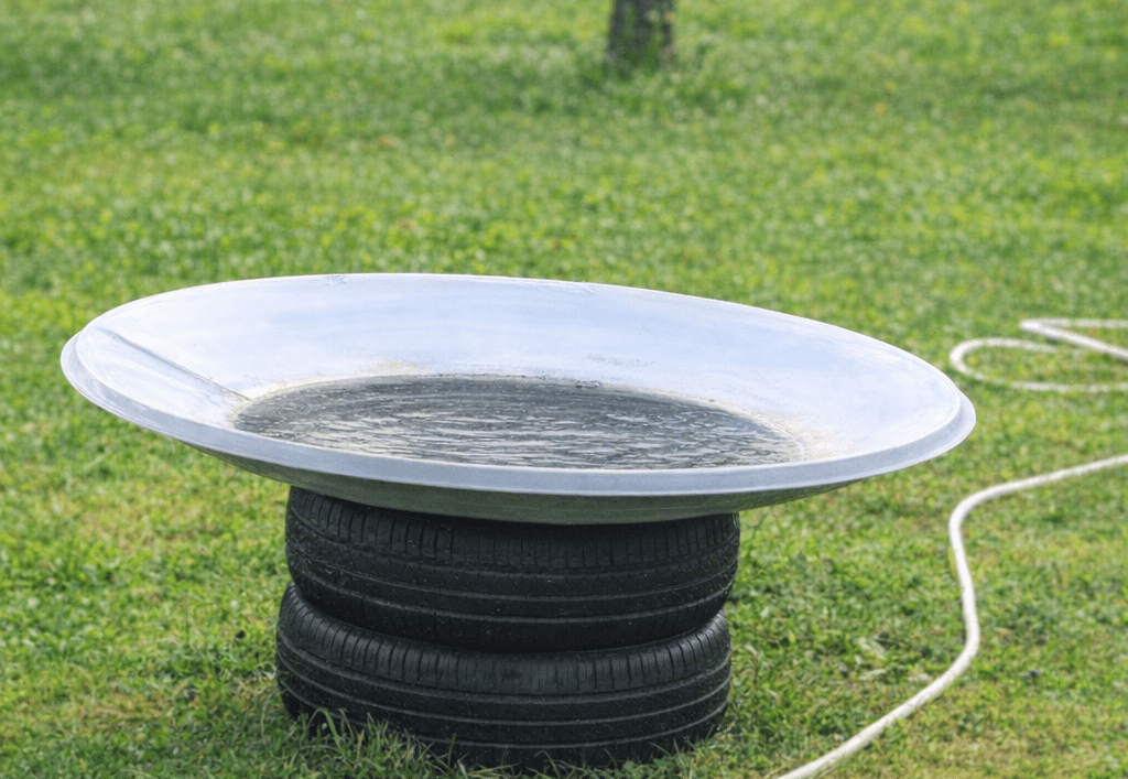 DIY garden fountain made from two stacked car tyres and a repurposed satellite dish filled with wate