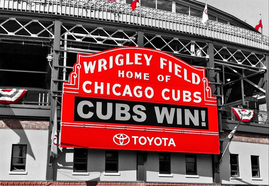 a large red and white sign that says cubs win at wrigley field