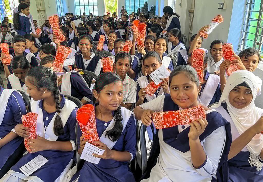 Large classroom of girls holding p washable napkin packs..