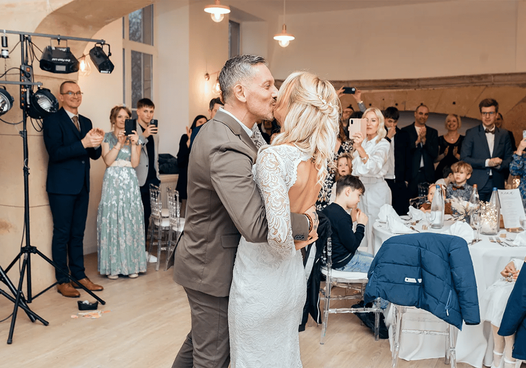 Premier baiser des mariés pendant la réception entourés de leurs invités. au Château de Puxe .