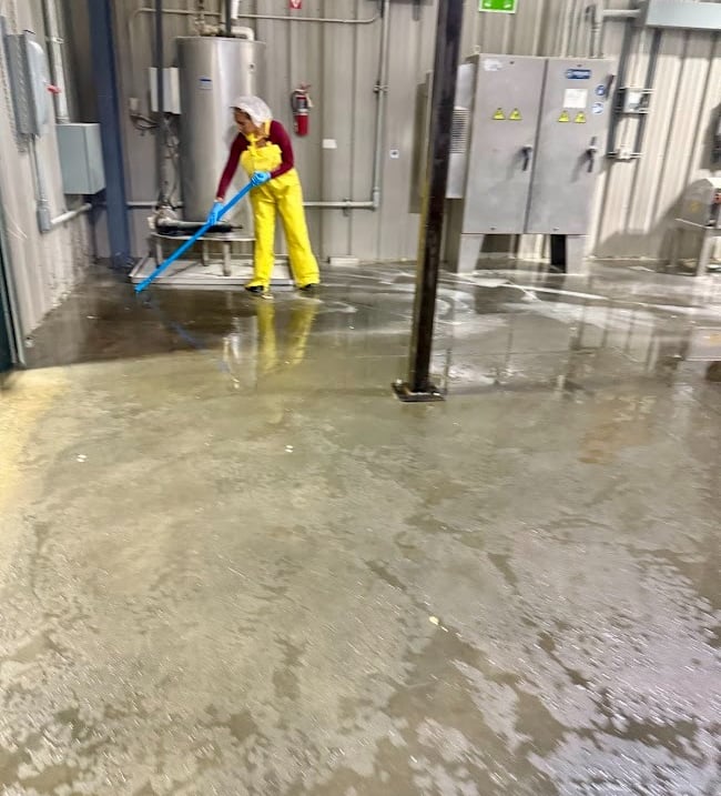 CLEANING SPECIALIST DEEP CLEANS THE FLOOR AT AN INDUSTRIAL FACILITY