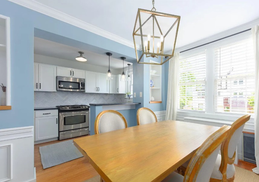 Photograph taken from a dining room looking through a large wall opening into a renovated kitchen