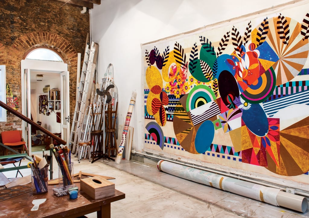 Ateliê de Beatriz Milhazes, colorido e cheio de obras e materiais de arte.