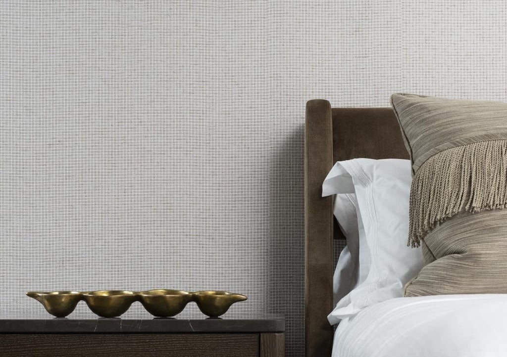 Luxury bedroom featuring textured light gray wallpaper, a brown velvet headboard, and elegant gold decor.