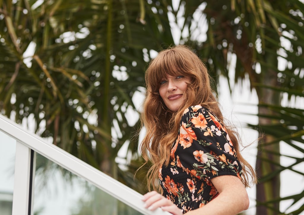 Fashion campaign photography - a woman in a floral dress standing on a balcony railing