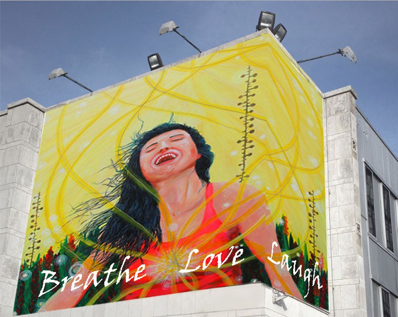 Mural of a joyful woman on a building with text saying Breathe Love Laugh.