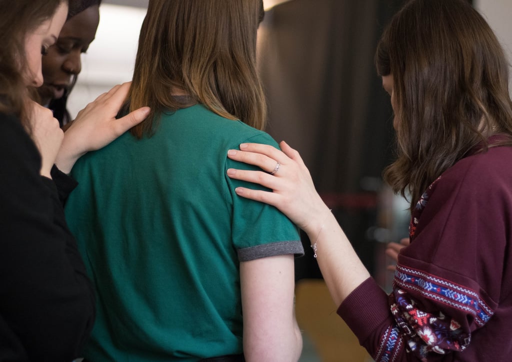 Three ladies laying hands on another lady in the middle