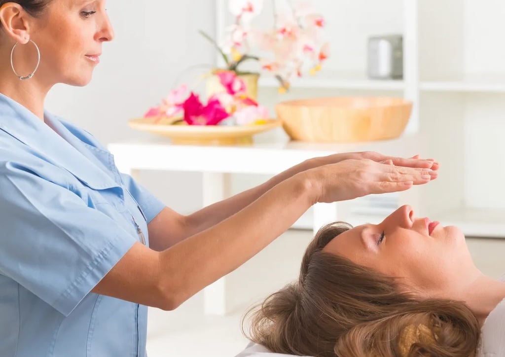 Hovering hands of standing Reiki practitioner over a woman's face who is laying down