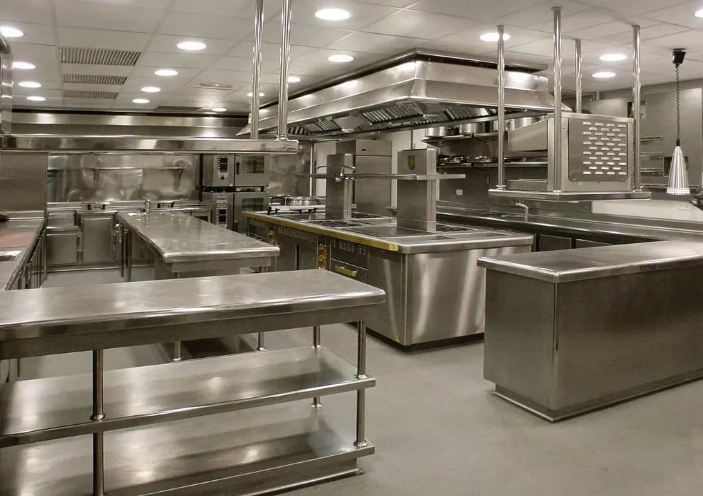 Complete stainless steel kitchen fit-out with custom work benches and exhaust hoods by the About SSB team.