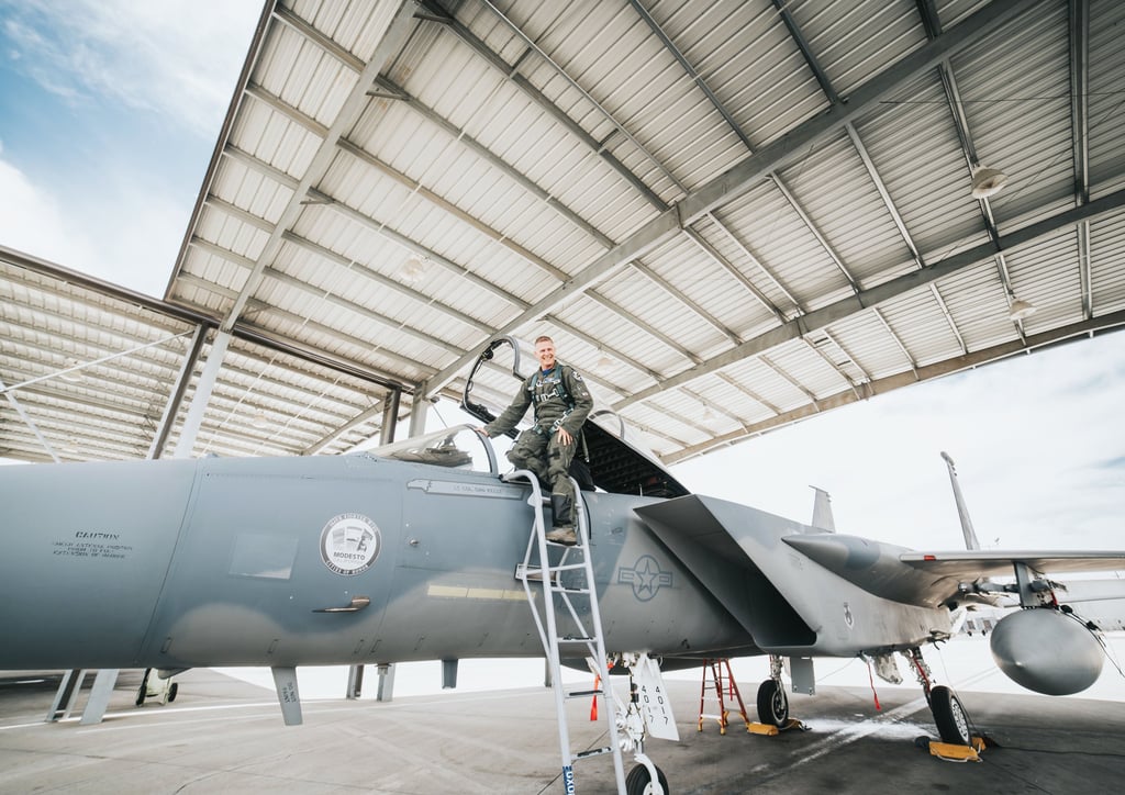 a man in a military uniform standing on a ladder of a fighter jet