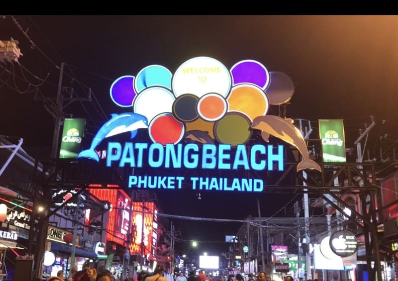 Beleuchtetes Neonschild von Patong Beach in Phuket, mit bunten Lichtern und Delfin-Figuren bei Nacht