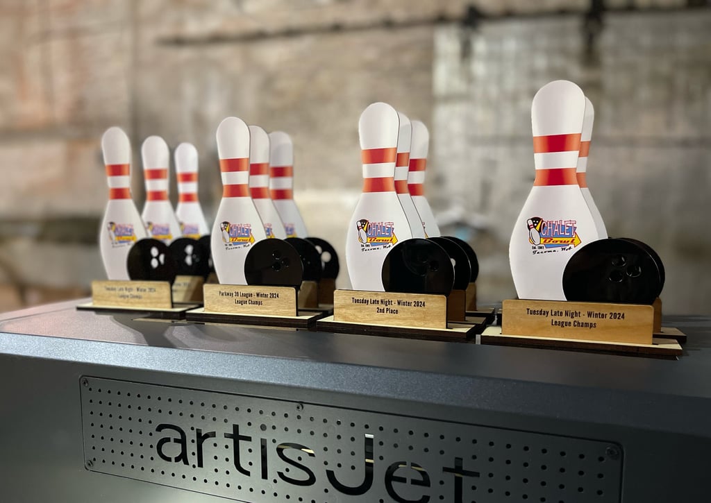 Custom UV printed bowling trophies featuring pins and balls on an artisJet printer bed.