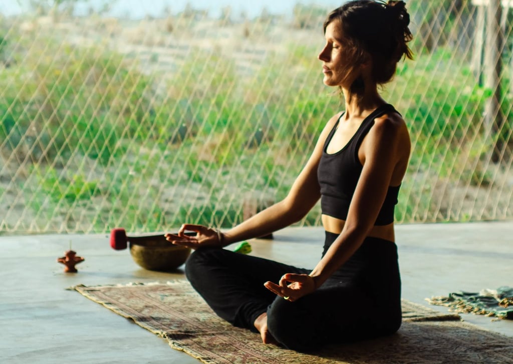 Isabel Maass meditating in yoga shala with afternoon sun, symbolizing demystifying meditation and mindful presence.