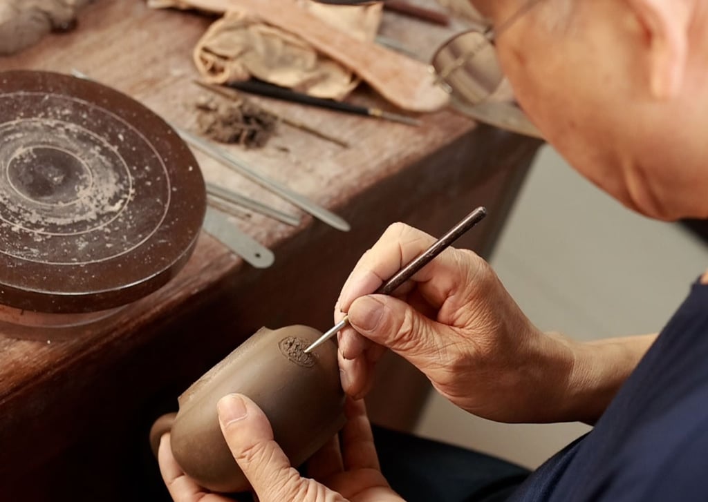 An artisan from TeapotArtisan handcrafting a Yixing teapot