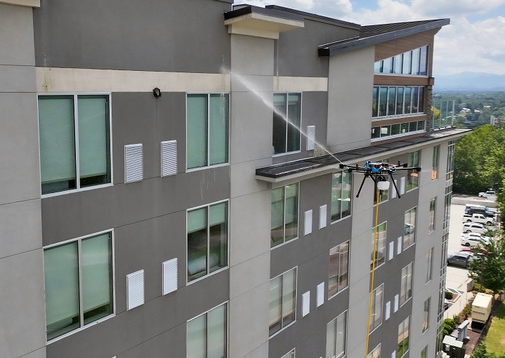 Drone pressure washing a large building