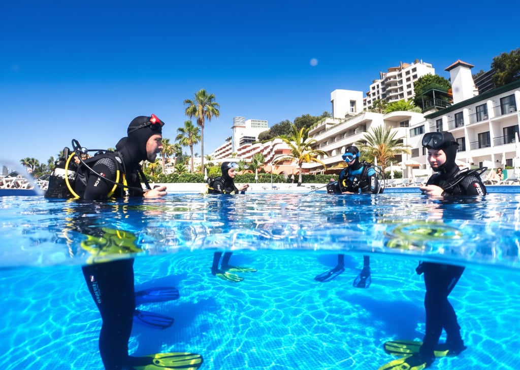 Scuba divers training in a clear blue Funchal resort pool, Madeira Island, under a sunny sky with coastal architecture.