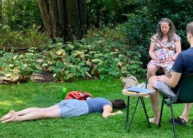 a group of people sitting in chairs in a grassy area