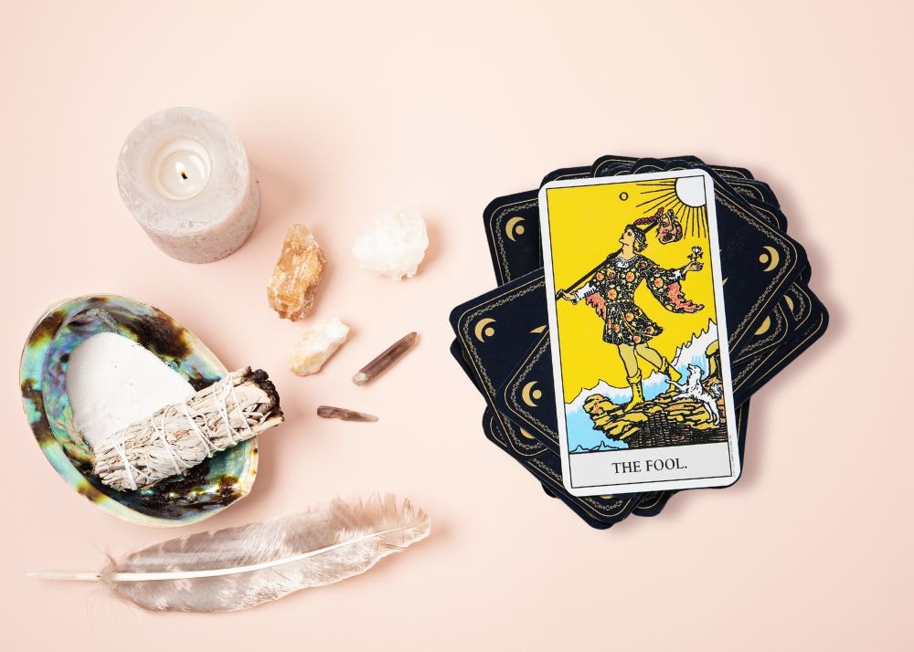 The Fool tarot card on a stack with crystals used in beginner tarot learning.