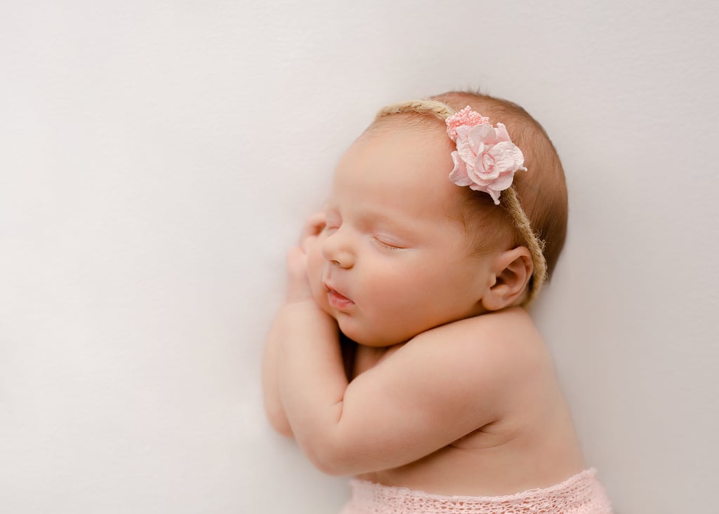a baby girl sleeping on her side with her hands on her chin