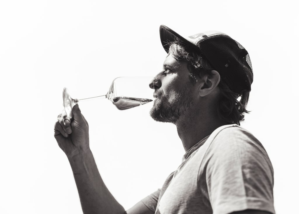 Ein Mann trinkt Wein und trägt eine Baseballmütze.