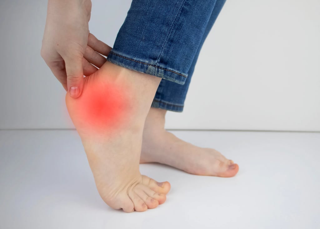 Woman holding her heel in pain highlighting heel pain and plantar fasciitis symptoms