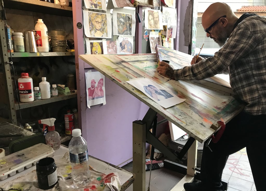 O artista em pé diante de uma tela, com uma expressão pensativa, enquanto decide o próximo mo