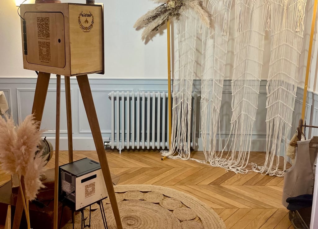 Photobooth en bois artisanal installé dans une scénographie bohème avec macramé, tapis et éclairage