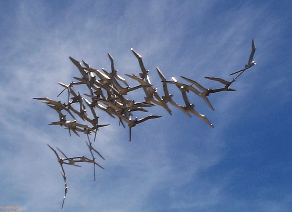 Steel sculpture of a flock of shearwaters in flight