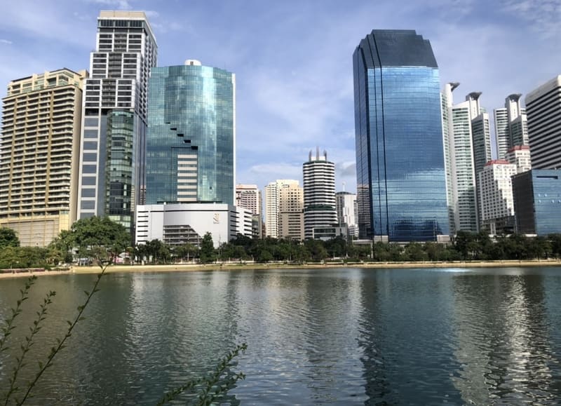 Moderne Wolkenkratzer der Skyline von Bangkok spiegeln sich im ruhigen Wasser des Sees im Benjakitti