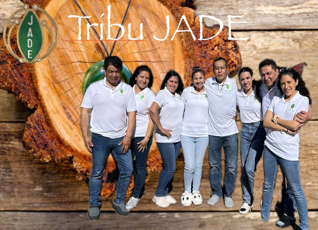 Tribu Jade team members posing in white polo shirts against a rustic wood log background.