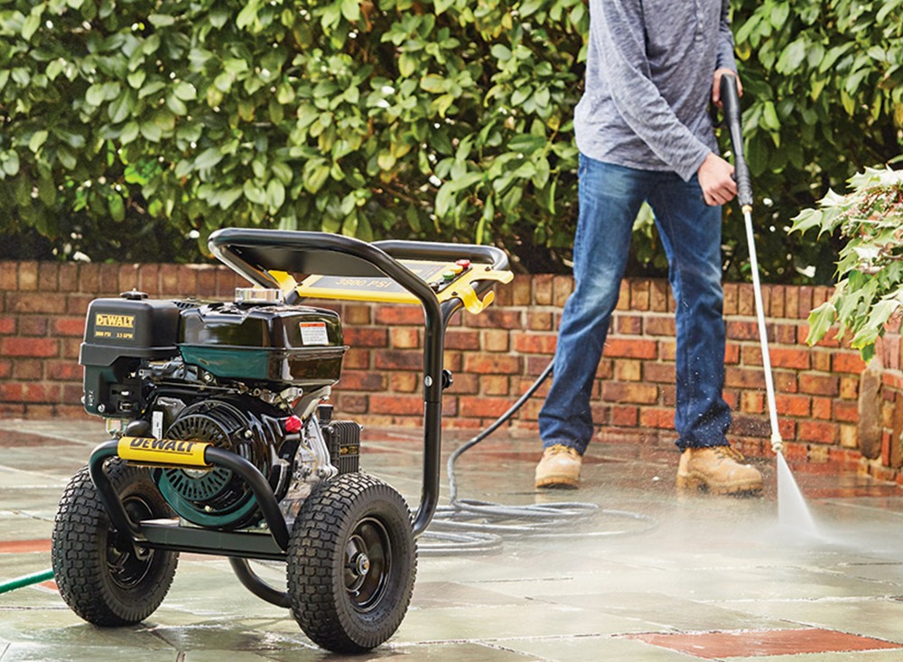 man cleaning a patio area with a pressure washer