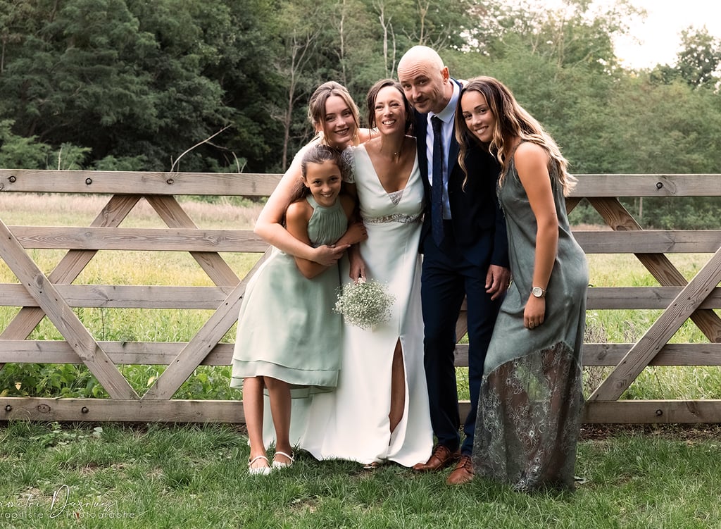 famille devant une clôture en bois qui pose pour une photo de mariage