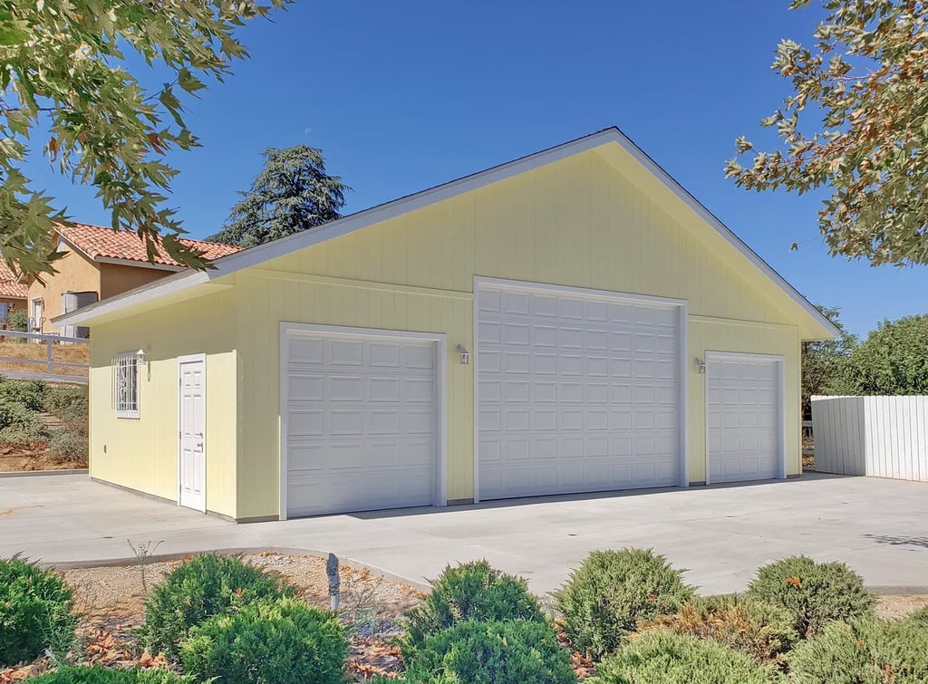 Large yellow RV garage with 3 white sectional doors.
