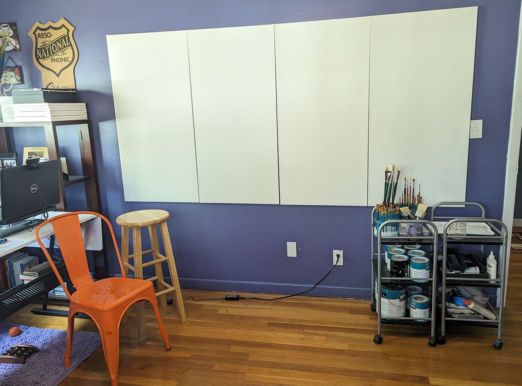 Four stretched canvas panels attached to a wall in an art studio ready for painting to begin.