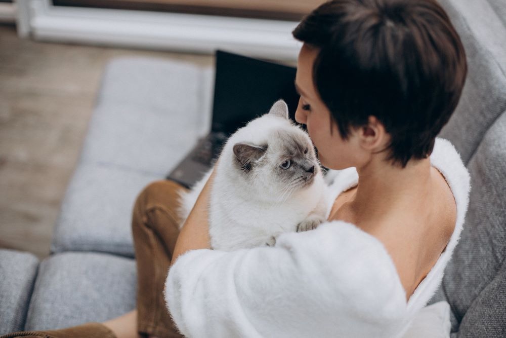 a woman in a bathrobear is holding a cat