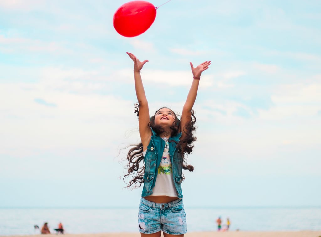 Little girl playing and trying to reach a red balloon