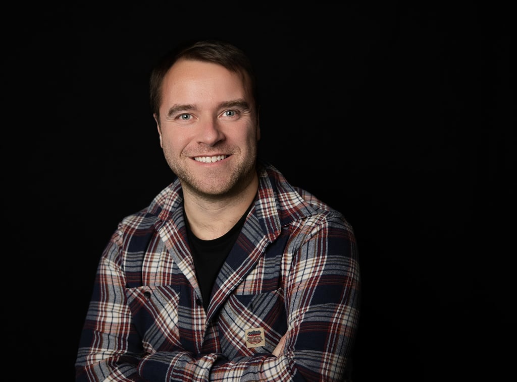 un homme souriant en chemise à carreaux