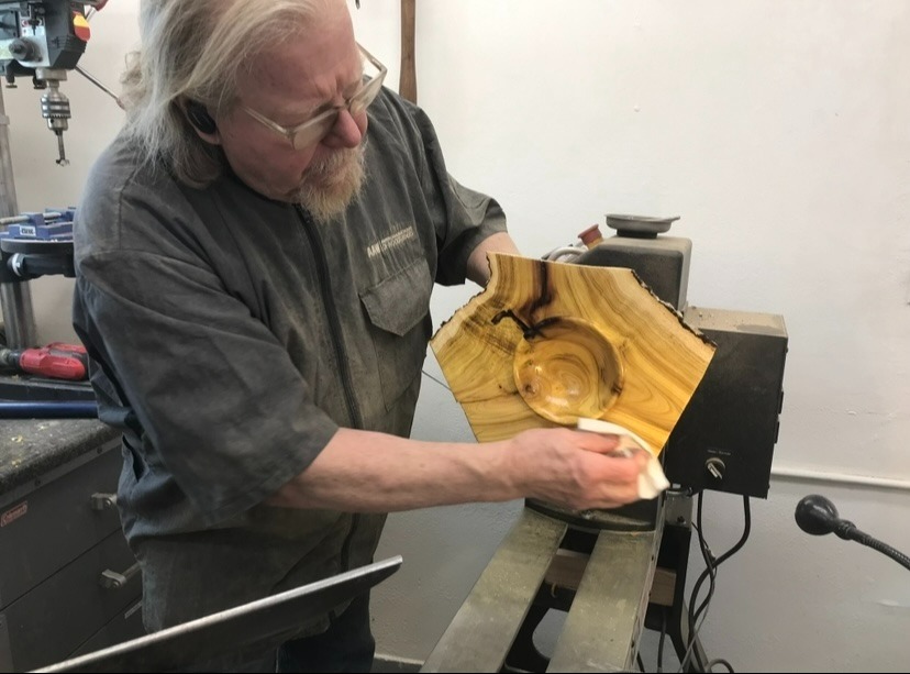Woodturner Tom Baker at the lathe applying oil to Mulberry Crotch Natural Edge Winged Bowl