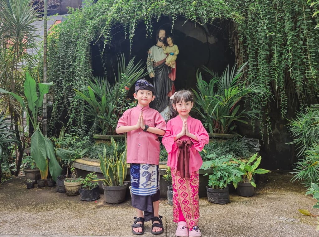 Two children in traditional pink Balinese clothing posing.