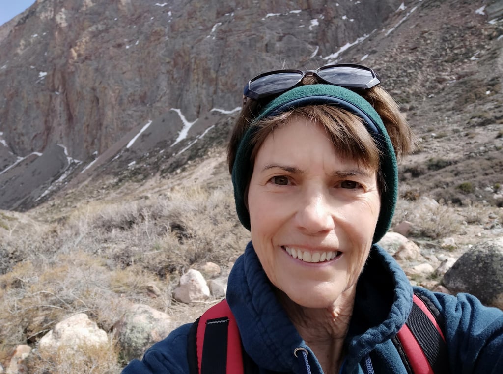 Susan Rensberger in the rugged Andes mountains wearing a headband and sunglasses on her head