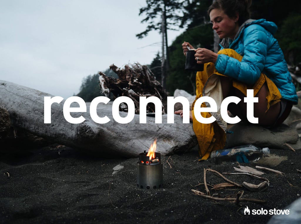 Woman sitting on the beach with small Solo Stove 