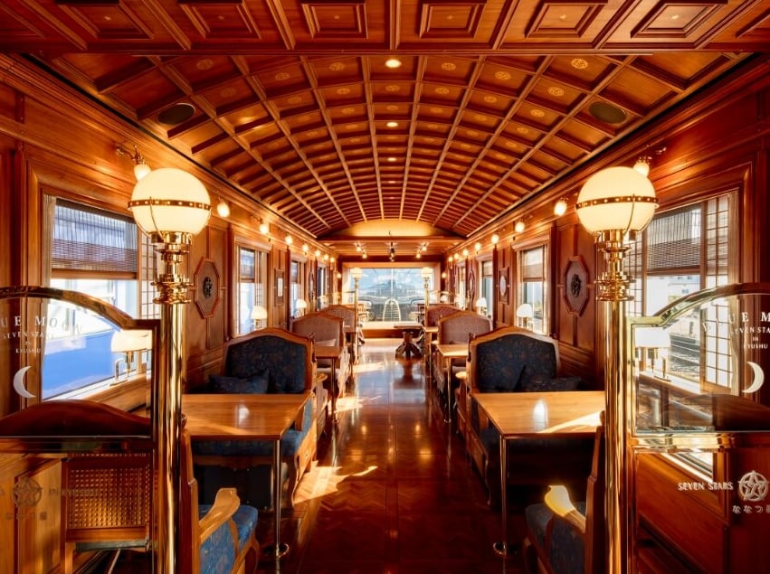 Luxury lounge interior of Seven Stars Kyushu train, featuring elegant wood paneling and bar seating.