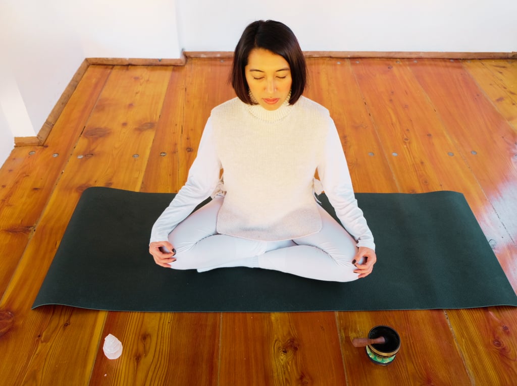 an asian woman sitted on a lotus position on a green matt, wearing all white
