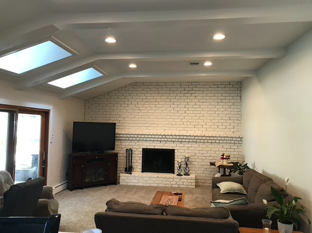 White painted brick fireplace updated living room renovation with skylights and recessed lighting